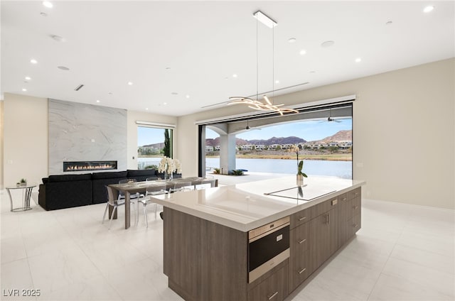 kitchen featuring a spacious island, modern cabinets, light countertops, and a high end fireplace