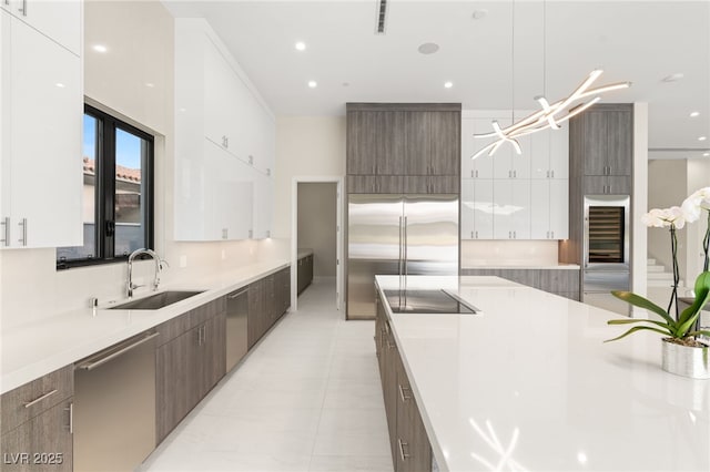 kitchen featuring light countertops, appliances with stainless steel finishes, white cabinets, modern cabinets, and a sink