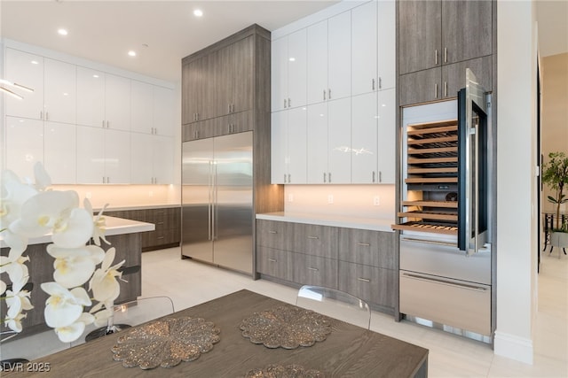 kitchen with stainless steel built in refrigerator, white cabinets, and modern cabinets