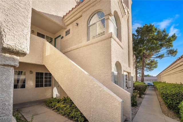 view of side of property featuring stucco siding and a tile roof