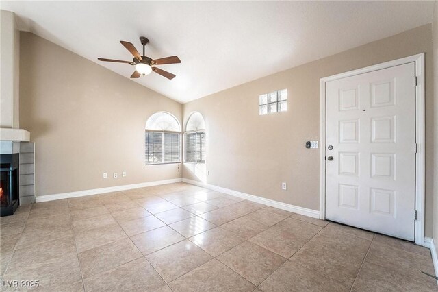 tiled entrance foyer featuring baseboards, plenty of natural light, lofted ceiling, and a warm lit fireplace