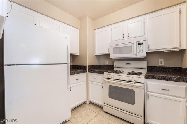 kitchen with white cabinetry, white appliances, light tile patterned floors, and dark countertops