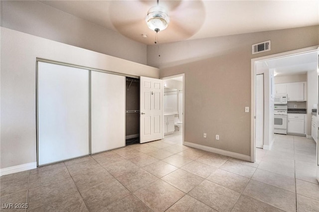 unfurnished bedroom with visible vents, baseboards, lofted ceiling, a closet, and ensuite bath