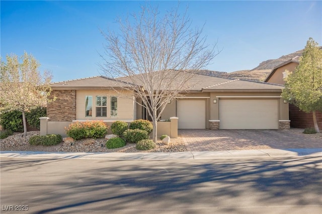 view of front of house featuring stone siding, stucco siding, decorative driveway, and a garage