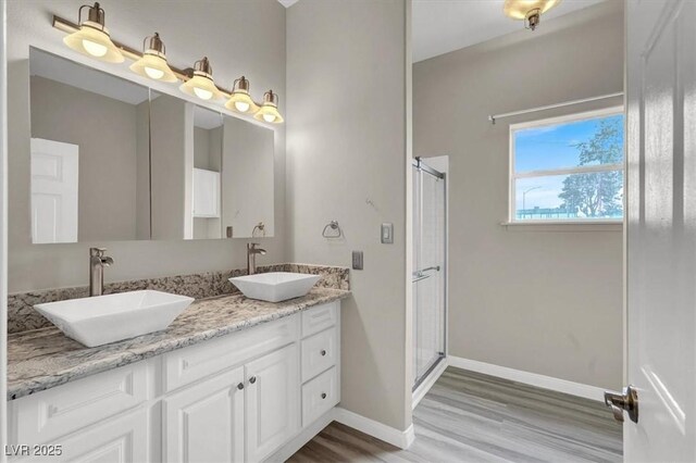 bathroom with a shower stall, wood finished floors, baseboards, and a sink