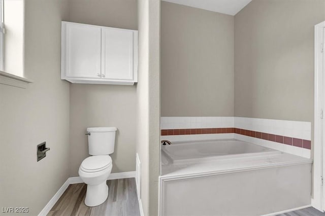 full bathroom with a garden tub, baseboards, toilet, and wood finished floors