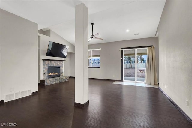 unfurnished living room with visible vents, lofted ceiling, a fireplace, wood finished floors, and a ceiling fan