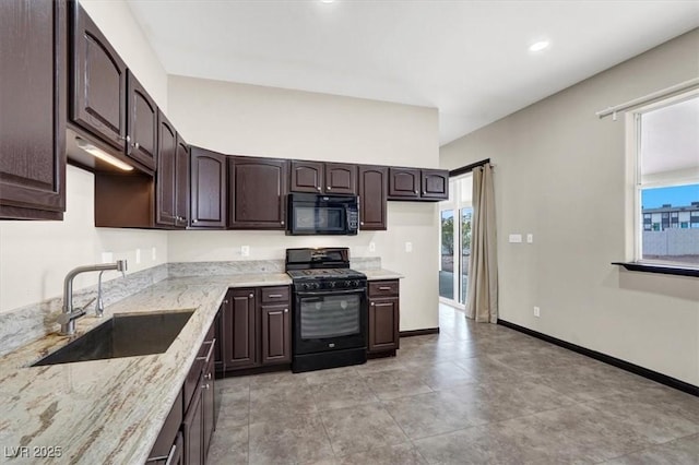 kitchen with light stone counters, baseboards, a sink, black appliances, and dark brown cabinets