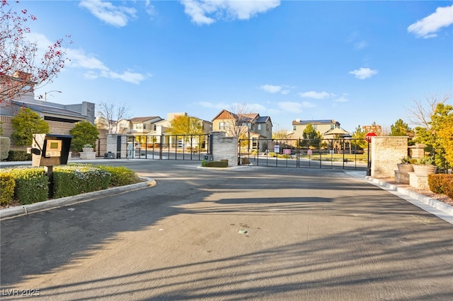 view of street with a gate, curbs, a residential view, and a gated entry