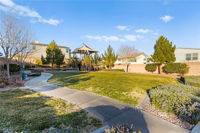 view of property's community featuring fence, a lawn, and playground community