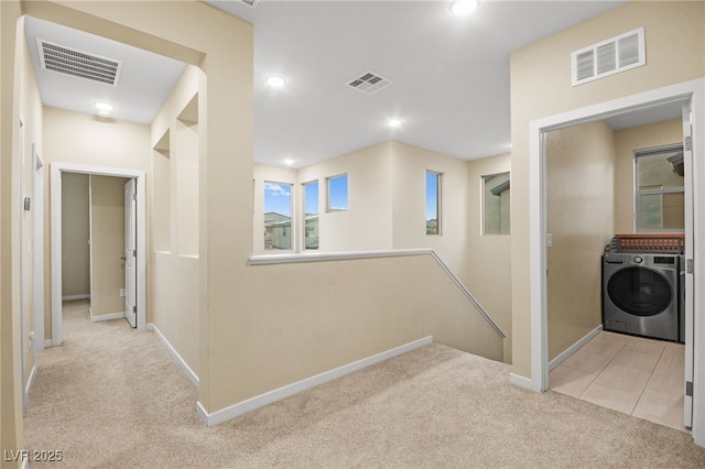 hall with visible vents, an upstairs landing, and light colored carpet