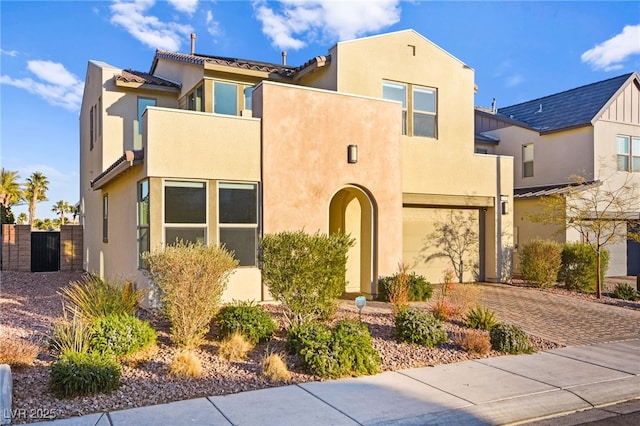 view of front of property with a gate, fence, an attached garage, stucco siding, and decorative driveway