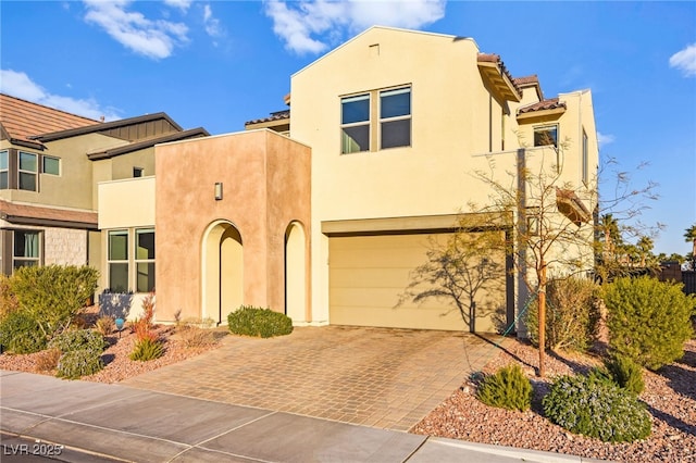 view of front of house with stucco siding, decorative driveway, a garage, and a tile roof