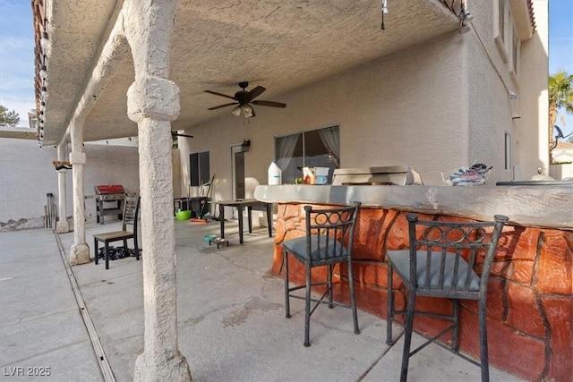 view of patio / terrace with outdoor wet bar, a grill, and ceiling fan