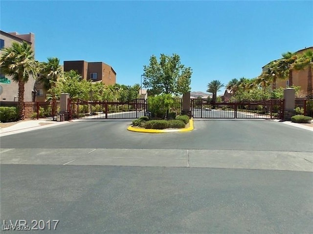 view of street with curbs, a gated entry, sidewalks, and a gate