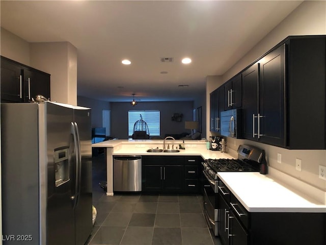 kitchen featuring visible vents, a sink, dark cabinetry, appliances with stainless steel finishes, and a peninsula