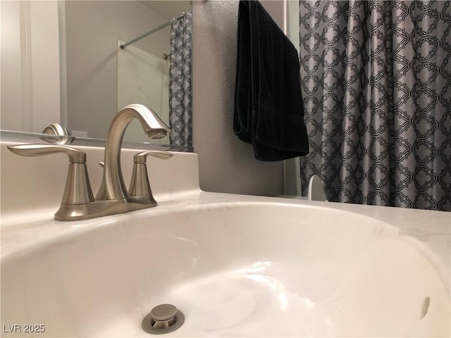 details with a shower with shower curtain and a sink