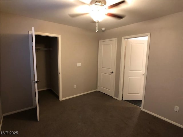 unfurnished bedroom with baseboards, dark colored carpet, a closet, and ceiling fan