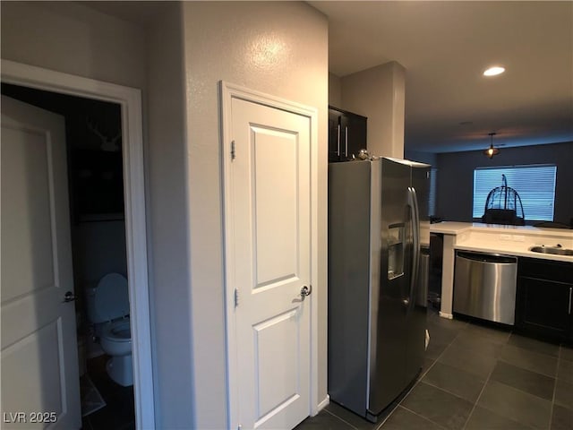 kitchen featuring recessed lighting, a sink, light countertops, appliances with stainless steel finishes, and dark tile patterned floors