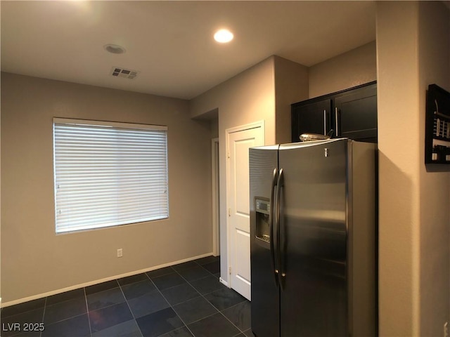 kitchen featuring visible vents, refrigerator with ice dispenser, dark tile patterned floors, dark cabinetry, and baseboards