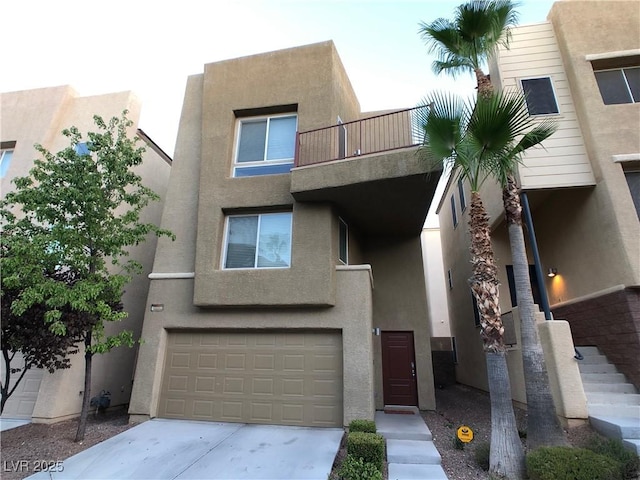 view of front facade featuring stucco siding, a balcony, a garage, and driveway