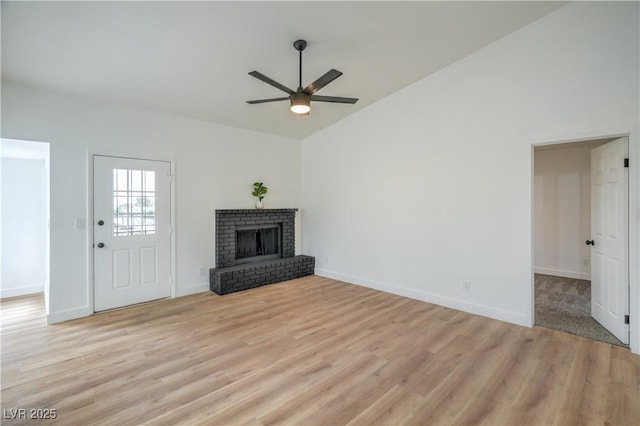 unfurnished living room with a brick fireplace, baseboards, light wood-type flooring, high vaulted ceiling, and a ceiling fan