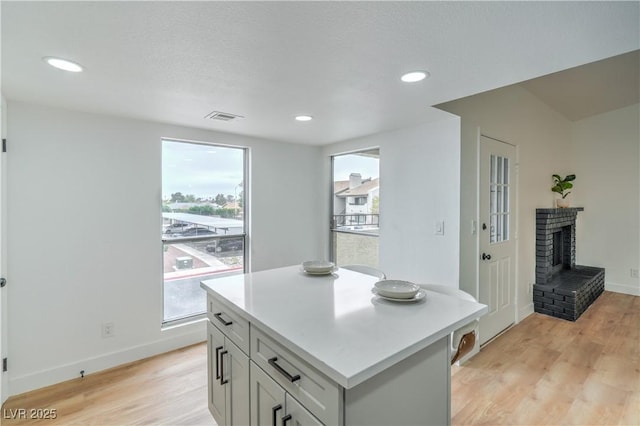 kitchen featuring light countertops, a fireplace, visible vents, and light wood-type flooring