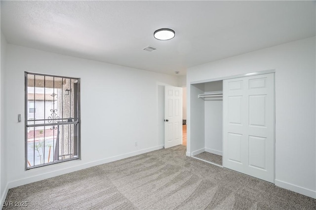 unfurnished bedroom with a closet, baseboards, carpet, and visible vents