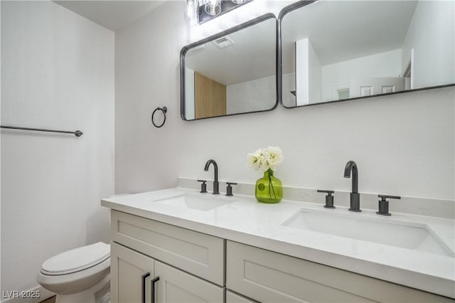 bathroom with a sink, visible vents, toilet, and double vanity