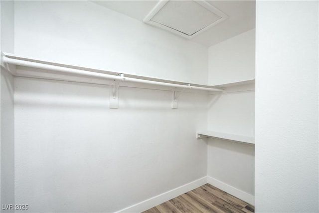 walk in closet featuring attic access and wood finished floors