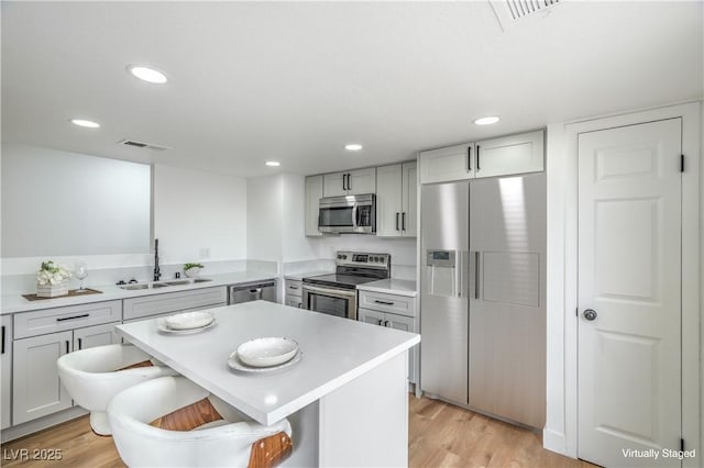 kitchen with visible vents, light wood-style flooring, a sink, light countertops, and appliances with stainless steel finishes