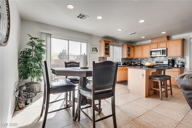 kitchen with visible vents, a sink, stainless steel microwave, dark countertops, and decorative backsplash