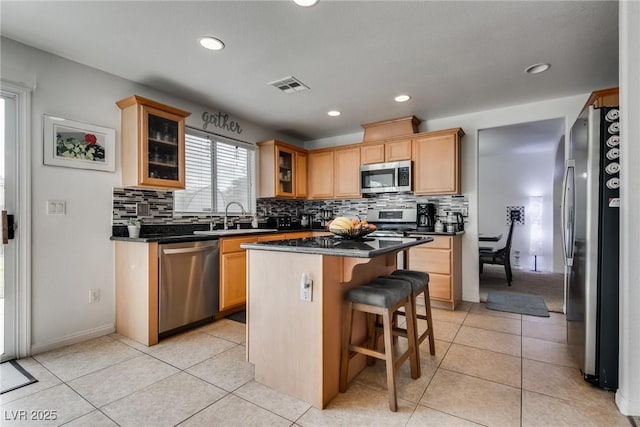 kitchen with visible vents, a center island, a breakfast bar, light tile patterned floors, and appliances with stainless steel finishes