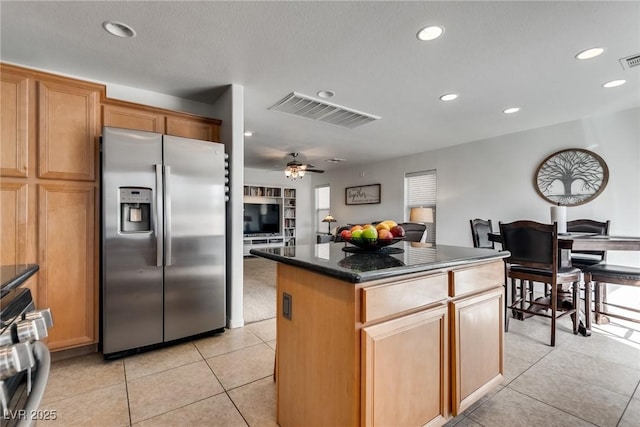 kitchen with visible vents, a center island, light tile patterned floors, stainless steel fridge, and range