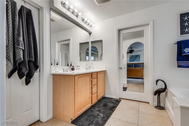 full bath featuring tile patterned floors, a garden tub, a sink, double vanity, and ceiling fan