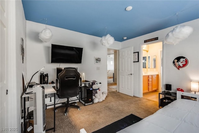 bedroom with ensuite bathroom and light carpet