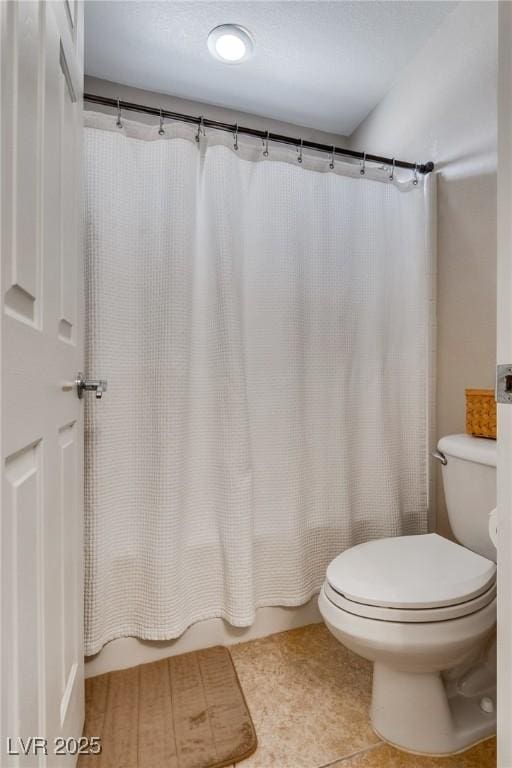 bathroom with toilet, shower / bath combo, and tile patterned flooring