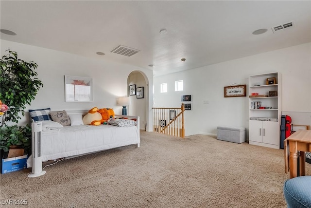 carpeted bedroom featuring arched walkways and visible vents