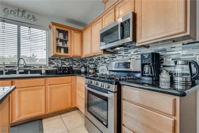 kitchen with light brown cabinets, light tile patterned flooring, a sink, appliances with stainless steel finishes, and backsplash