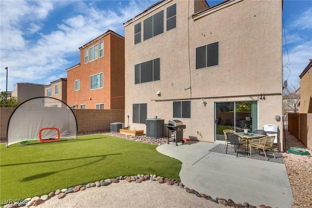 back of house with central AC, stucco siding, a lawn, a fenced backyard, and a patio