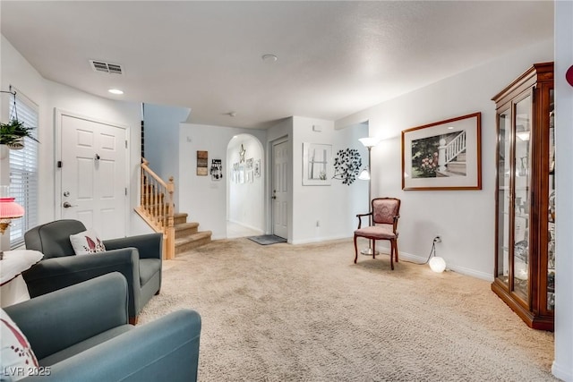 living room with stairway, carpet, visible vents, baseboards, and arched walkways