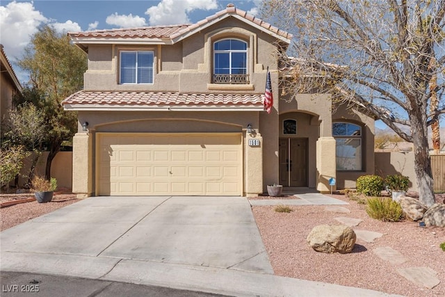 mediterranean / spanish-style home with concrete driveway, a tiled roof, an attached garage, and stucco siding