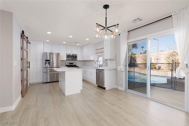 kitchen featuring visible vents, light countertops, a barn door, appliances with stainless steel finishes, and a sink