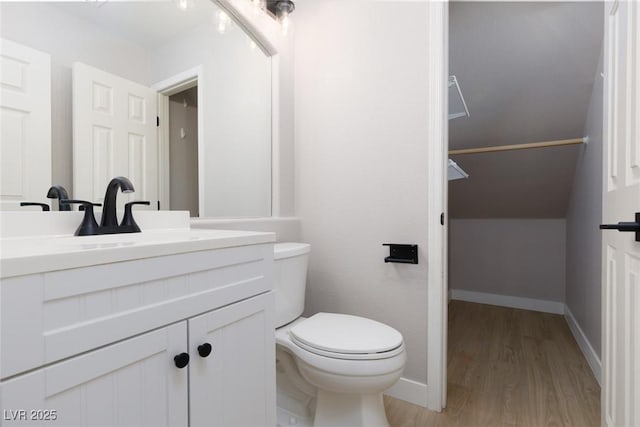 bathroom featuring vanity, toilet, wood finished floors, and baseboards