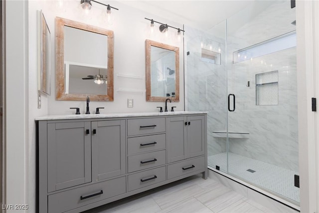 bathroom featuring double vanity, a ceiling fan, a marble finish shower, and a sink