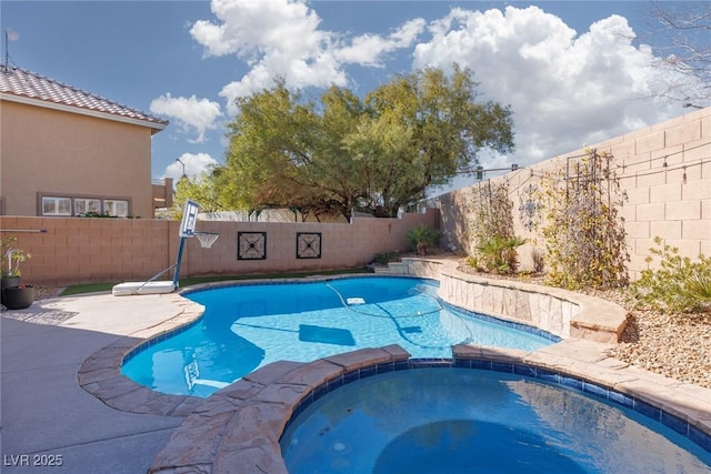 view of pool with a fenced backyard and a pool with connected hot tub