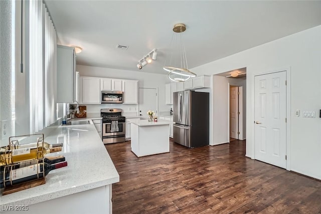 kitchen with visible vents, a center island, decorative light fixtures, stainless steel appliances, and dark wood-style flooring