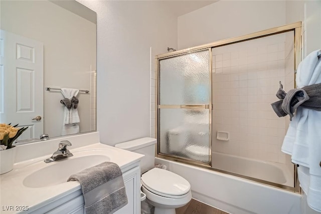 bathroom with vanity, toilet, and shower / bath combination with glass door