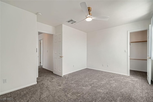 unfurnished bedroom featuring visible vents, baseboards, carpet, and a walk in closet