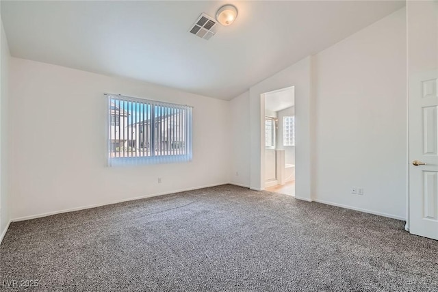 carpeted spare room with lofted ceiling, baseboards, and visible vents